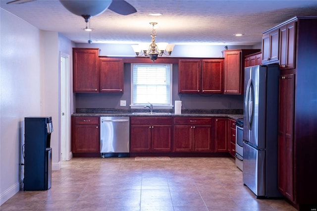 kitchen featuring dark brown cabinets, appliances with stainless steel finishes, a sink, and an inviting chandelier