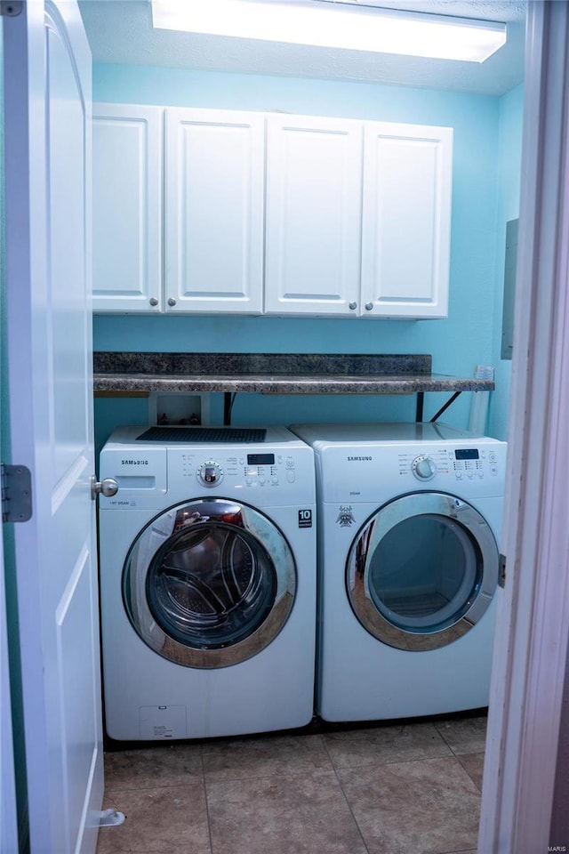 washroom with tile patterned floors, cabinet space, and washing machine and clothes dryer