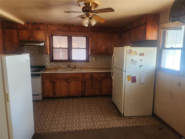 kitchen with white appliances, a sink, light countertops, under cabinet range hood, and brown cabinets