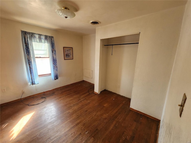 unfurnished bedroom featuring dark wood finished floors, visible vents, and a closet