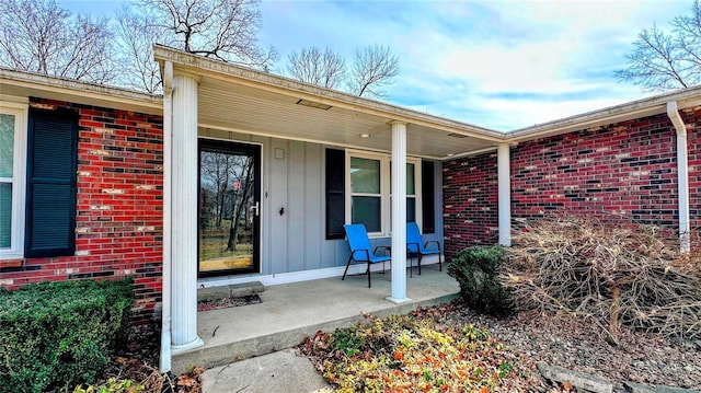 property entrance with a porch, brick siding, and board and batten siding