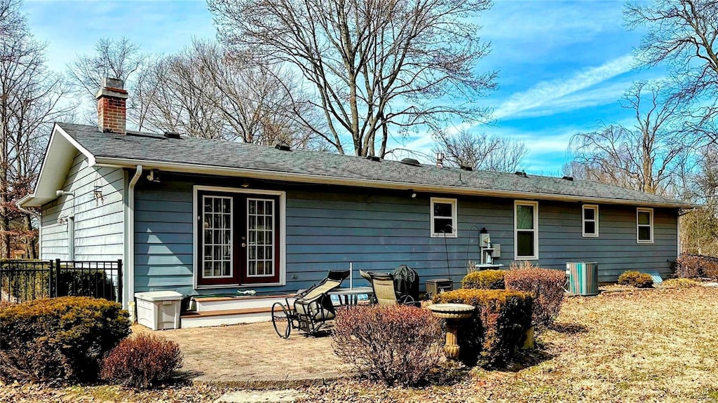 rear view of property featuring a patio area, central AC unit, a chimney, and fence