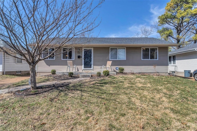 ranch-style home with a front yard and roof with shingles