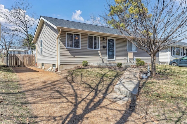 ranch-style house featuring fence and roof with shingles