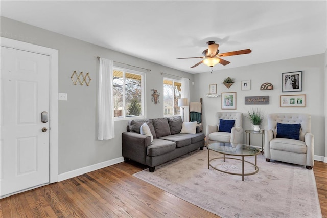 living area featuring a ceiling fan, wood finished floors, and baseboards