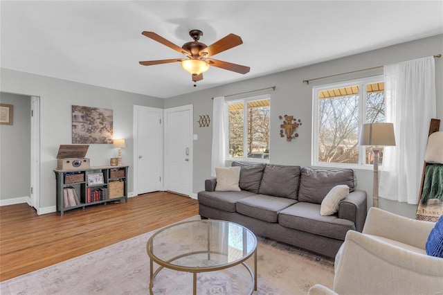 living area featuring baseboards, a ceiling fan, and wood finished floors