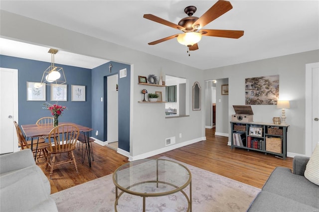 living room with visible vents, baseboards, wood finished floors, and a ceiling fan