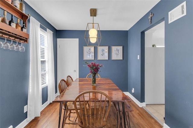 dining room with wood finished floors, baseboards, and visible vents