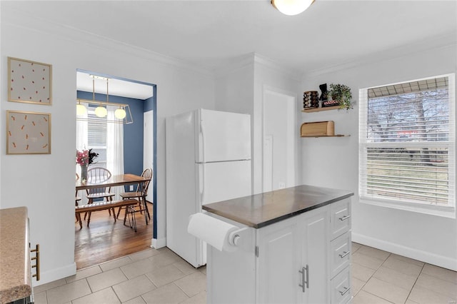 kitchen featuring crown molding, a chandelier, light tile patterned floors, freestanding refrigerator, and white cabinets