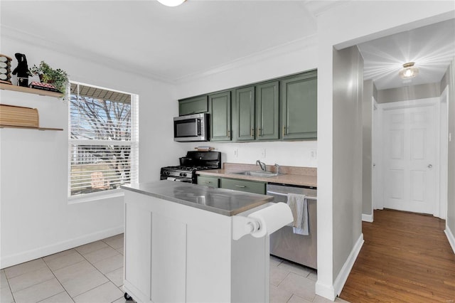 kitchen with green cabinets, baseboards, light tile patterned floors, appliances with stainless steel finishes, and a sink