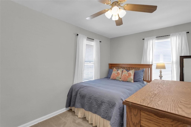 bedroom featuring light carpet, a ceiling fan, and baseboards