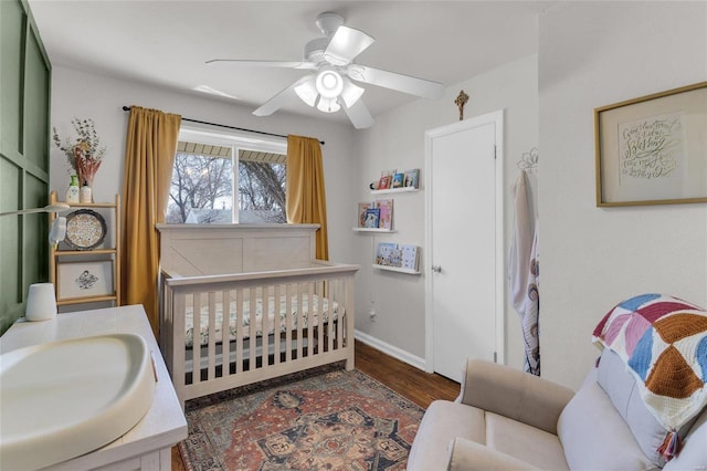 bedroom featuring a sink, baseboards, wood finished floors, and a ceiling fan