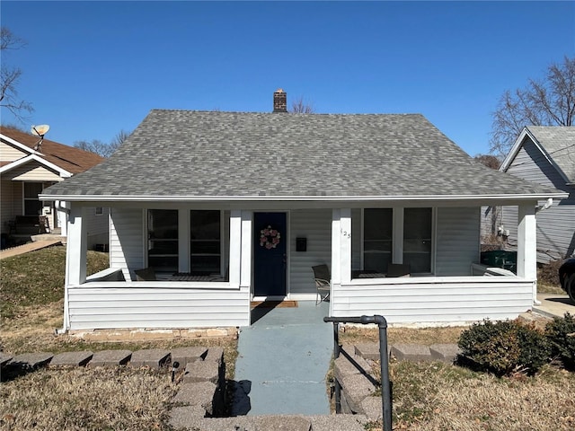 bungalow with covered porch, a chimney, and a shingled roof