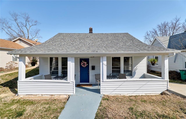 bungalow with a chimney, covered porch, and a shingled roof