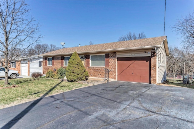 ranch-style home featuring brick siding, fence, aphalt driveway, a front yard, and a garage