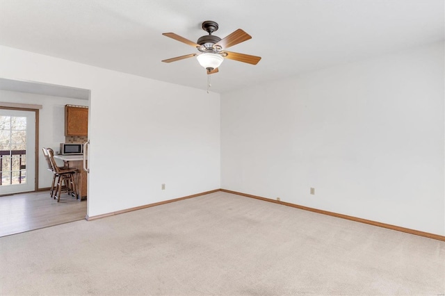 spare room featuring baseboards, light colored carpet, and a ceiling fan