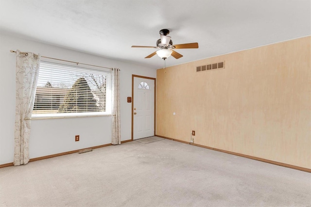 empty room featuring a ceiling fan, baseboards, visible vents, and light carpet