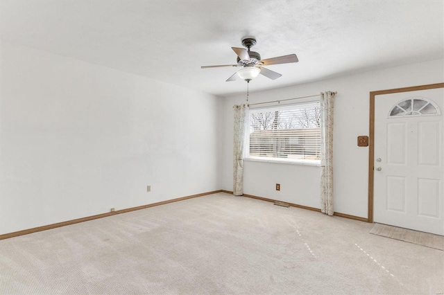 entrance foyer with baseboards, carpet floors, visible vents, and ceiling fan