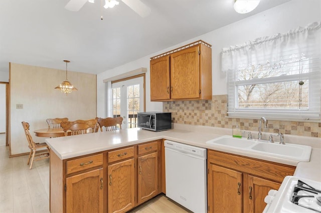 kitchen with range with gas stovetop, a peninsula, white dishwasher, a sink, and stainless steel microwave