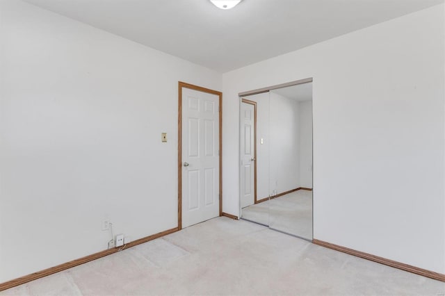 spare room featuring light carpet and baseboards