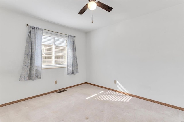 carpeted empty room with visible vents, ceiling fan, and baseboards