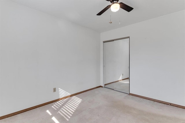 empty room featuring light carpet, a ceiling fan, and baseboards