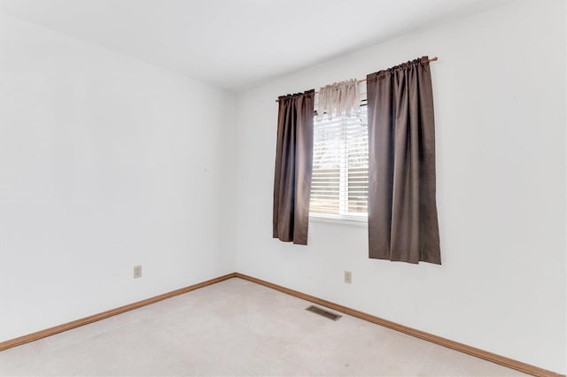 spare room featuring visible vents, baseboards, and light carpet