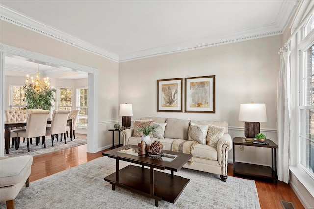 living area featuring an inviting chandelier, ornamental molding, and dark wood-style flooring