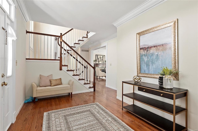 foyer with visible vents, ornamental molding, wood finished floors, baseboards, and stairs