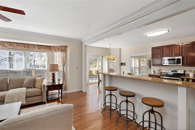 kitchen featuring open floor plan, a breakfast bar area, stainless steel appliances, and a healthy amount of sunlight