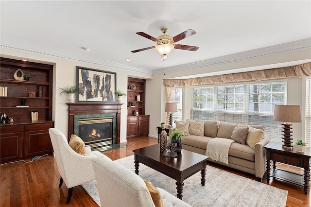 living area with crown molding, plenty of natural light, a ceiling fan, and a high end fireplace