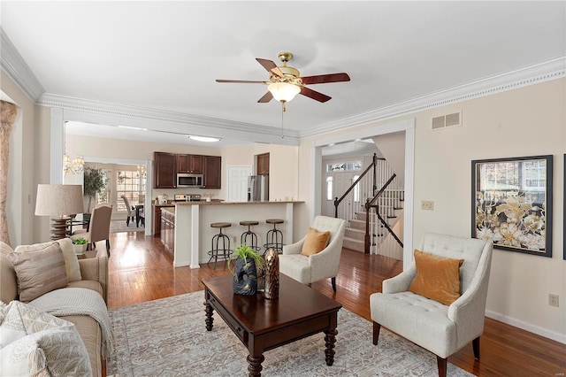 living room featuring visible vents, stairs, ceiling fan, and wood finished floors