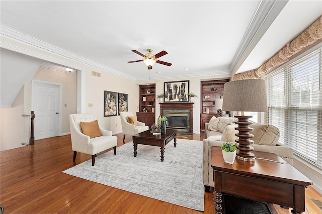 living room with a wealth of natural light, crown molding, a ceiling fan, and wood finished floors