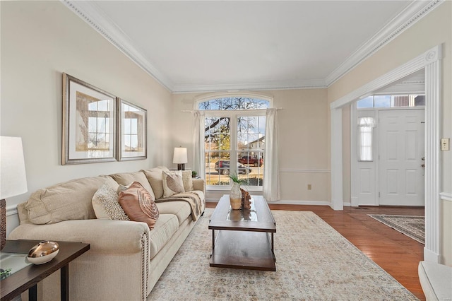 living area featuring wood finished floors, baseboards, and ornamental molding