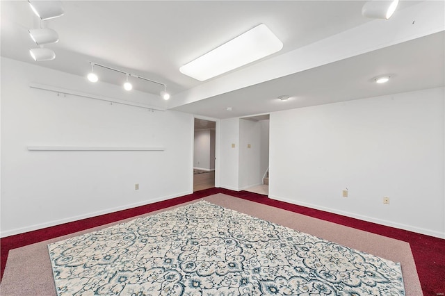 finished below grade area featuring rail lighting, stairway, baseboards, and carpet flooring