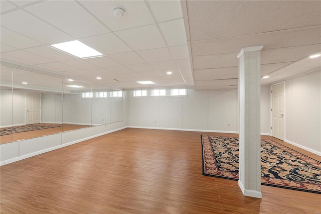 basement with a drop ceiling, recessed lighting, baseboards, and wood finished floors