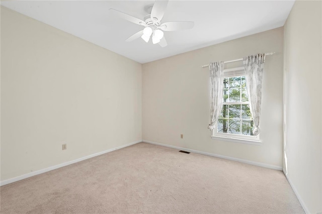 carpeted spare room with visible vents, baseboards, and ceiling fan