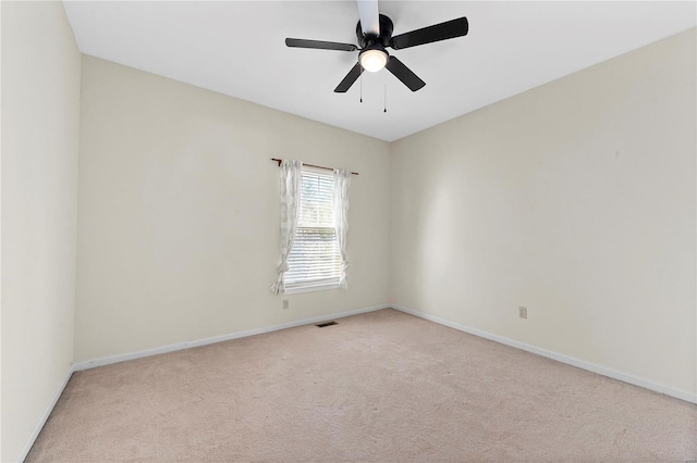 unfurnished room with a ceiling fan, light colored carpet, visible vents, and baseboards