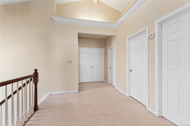 hallway featuring baseboards, an upstairs landing, light colored carpet, and high vaulted ceiling