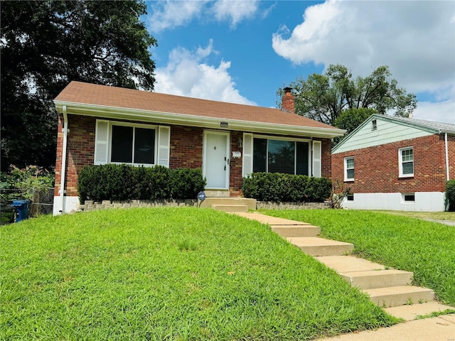 ranch-style home with brick siding, a chimney, and a front yard