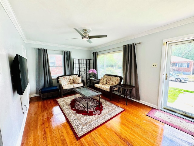 living area with crown molding, plenty of natural light, wood finished floors, and baseboards