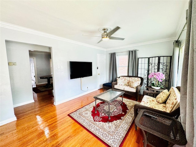 living area with ceiling fan, wood finished floors, baseboards, and ornamental molding