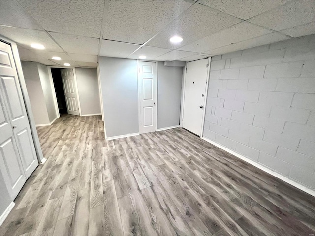 finished below grade area with recessed lighting, a paneled ceiling, baseboards, and wood finished floors