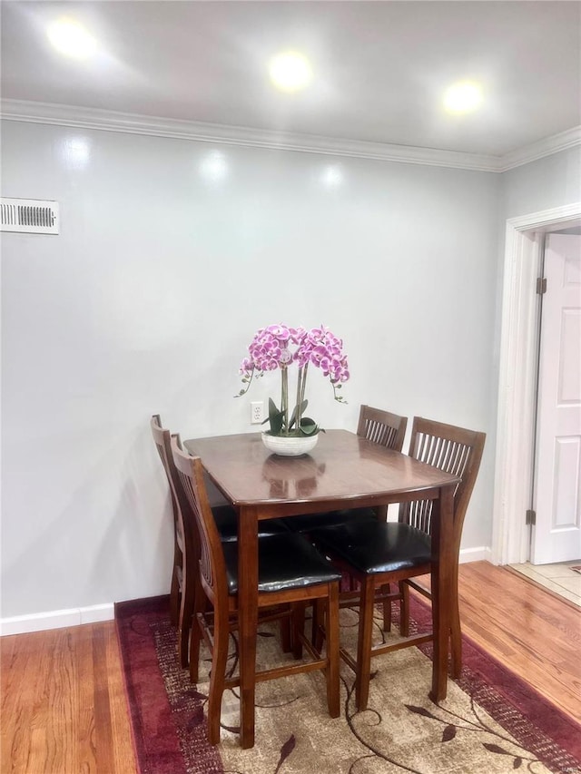 dining area featuring wood finished floors, visible vents, and ornamental molding