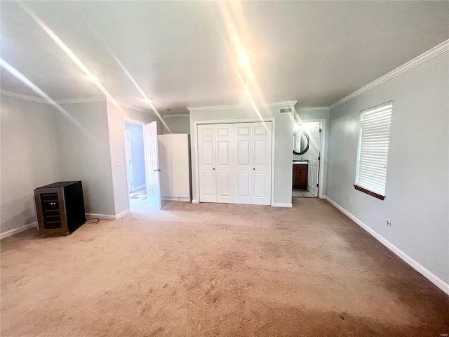 unfurnished bedroom featuring a closet, baseboards, light colored carpet, and crown molding