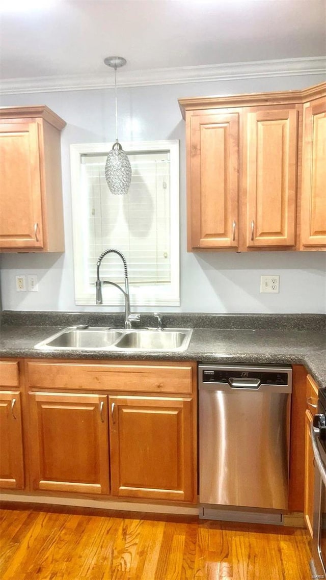 kitchen featuring dark countertops, light wood-type flooring, ornamental molding, stainless steel dishwasher, and a sink