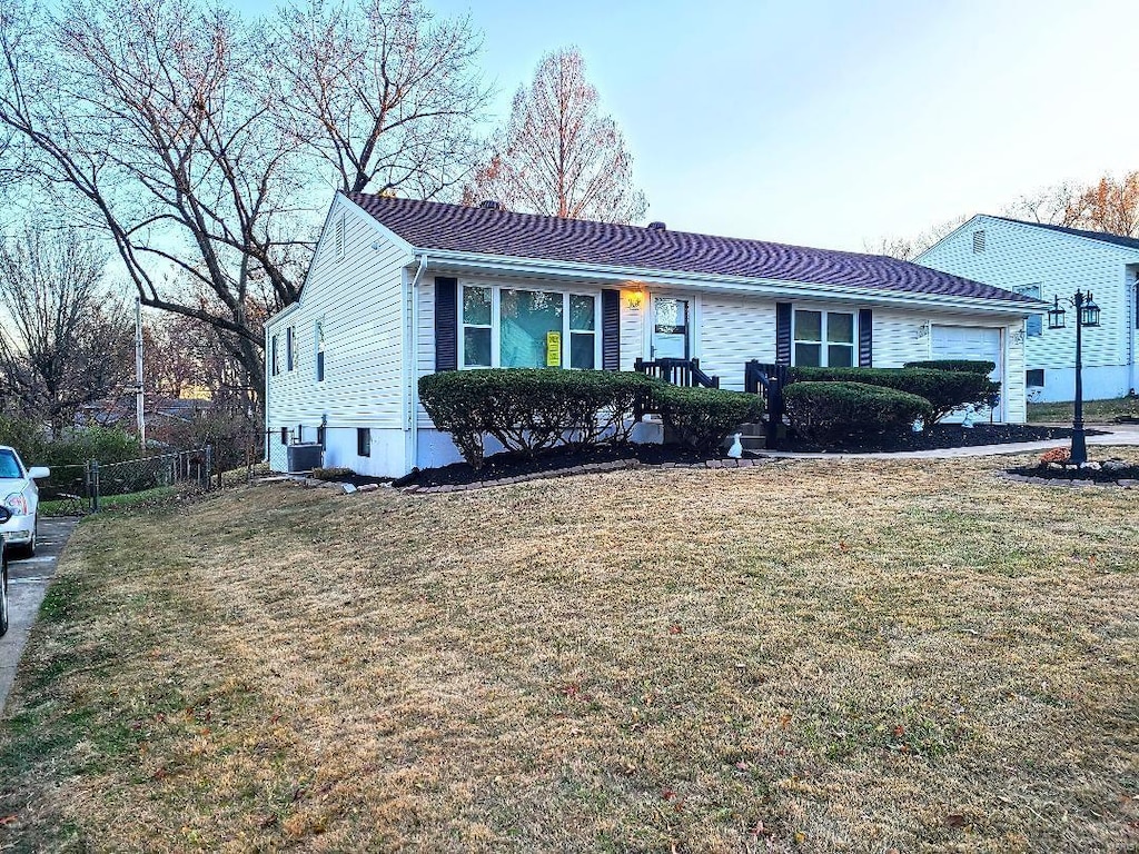 single story home with an attached garage, a front yard, and fence