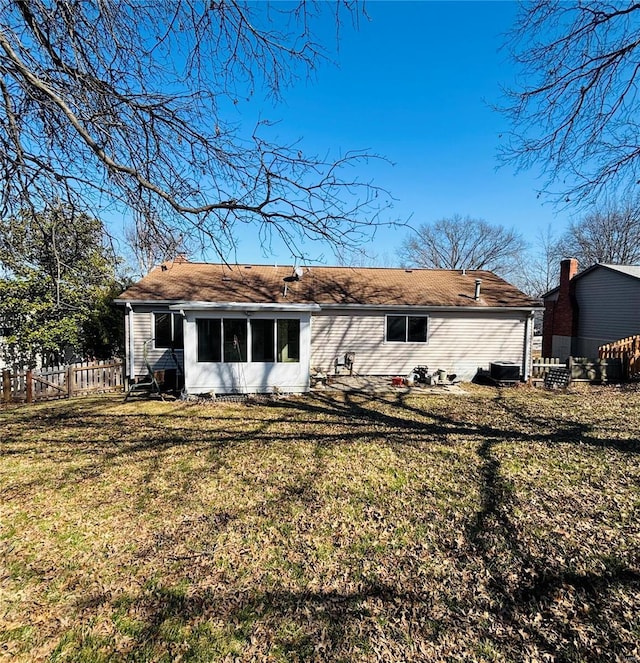 rear view of property featuring a sunroom, a yard, and fence