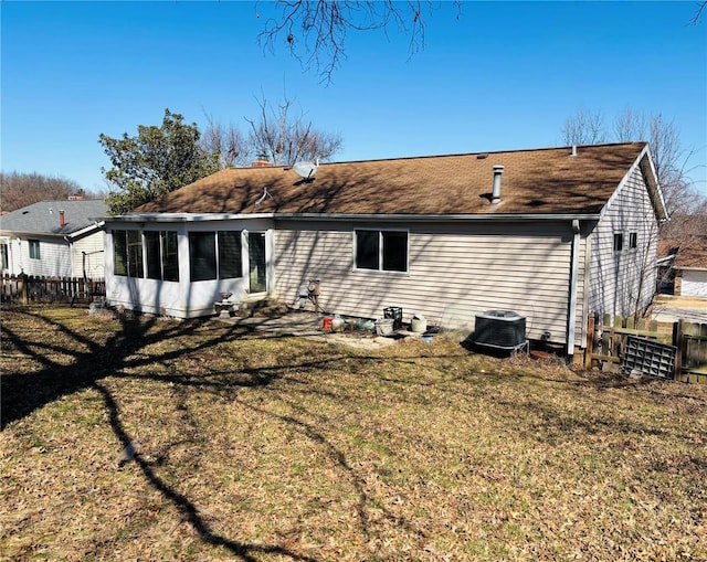 rear view of house with central AC unit, a yard, fence, and a sunroom