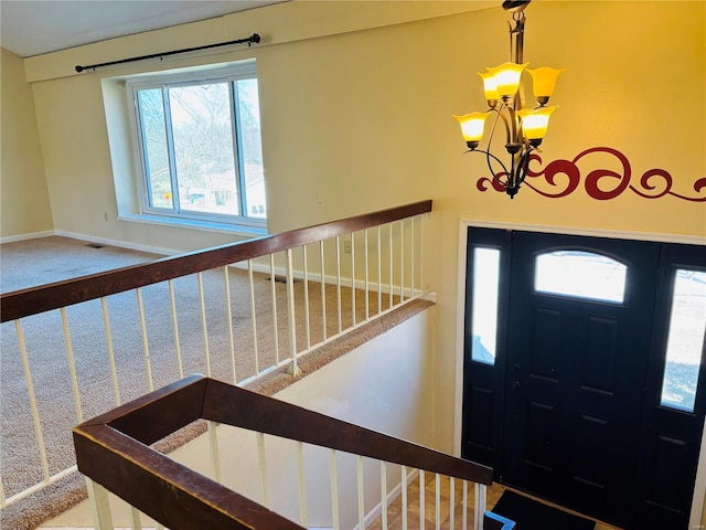 entrance foyer with a notable chandelier, visible vents, stairway, and baseboards